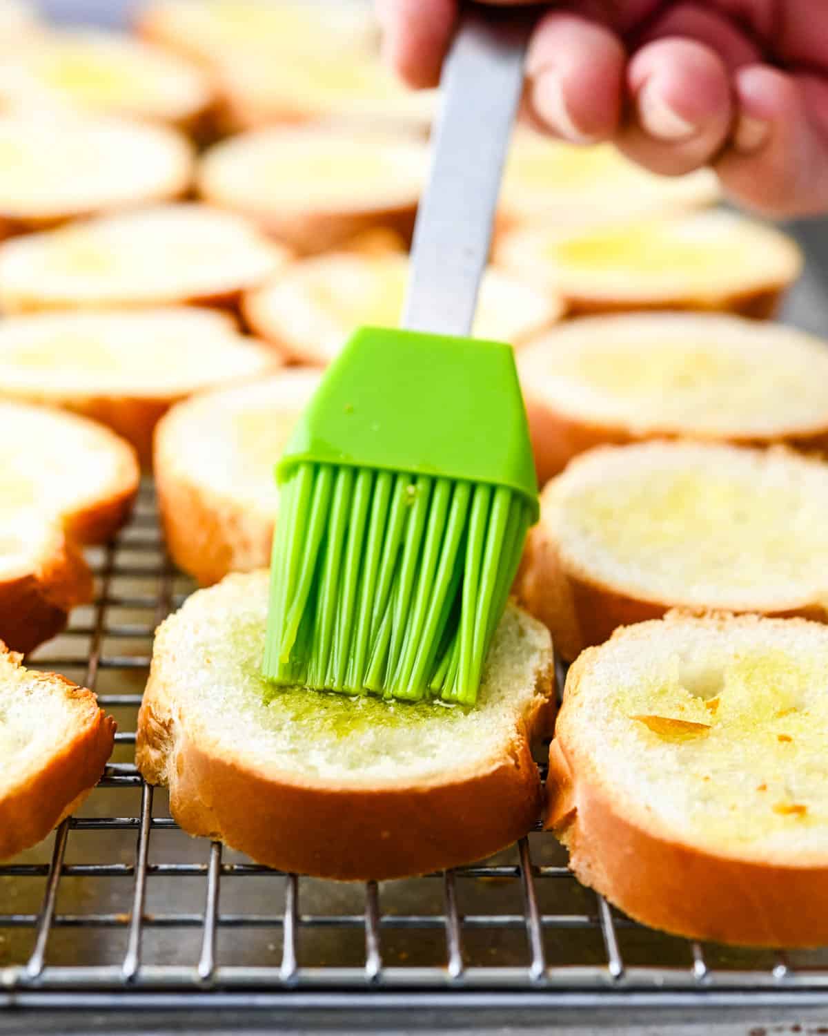 Brushing bread slices with olive oil.