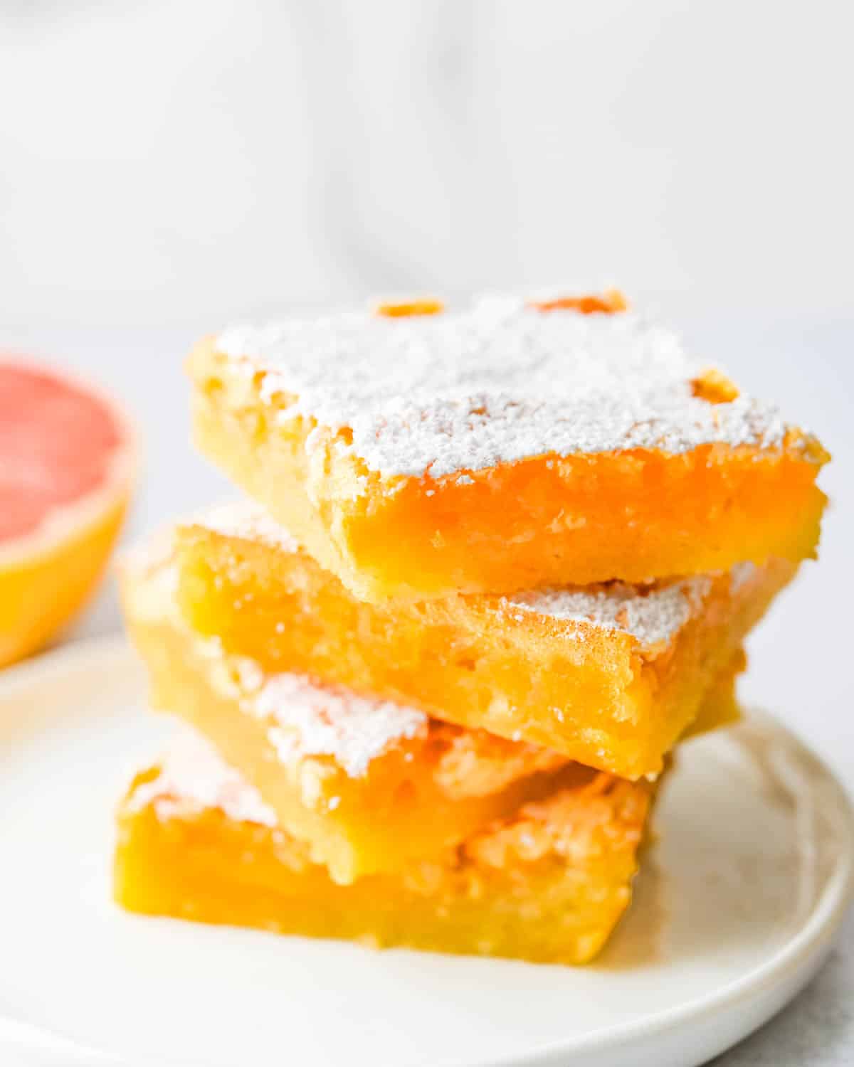 A stack of pink grapefruit bars with powdered sugar. 