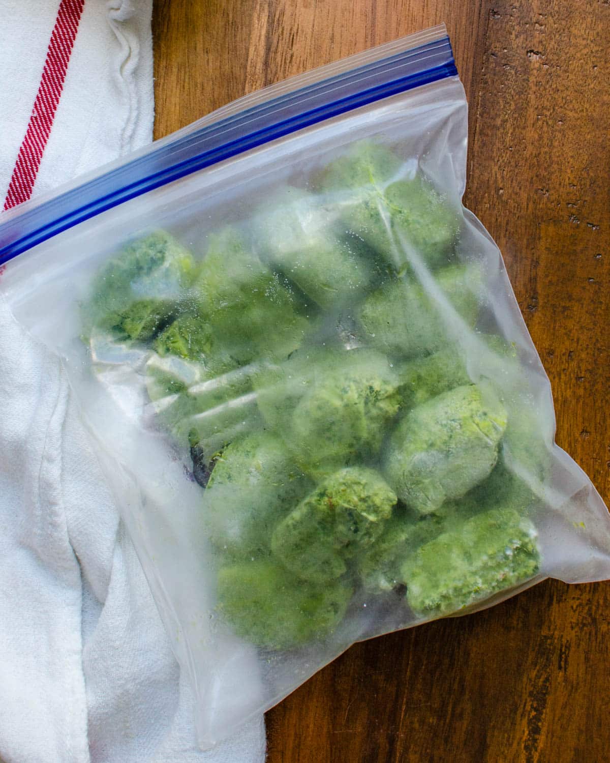 Placing the frozen basil pesto cubes into a freezer safe baggie.