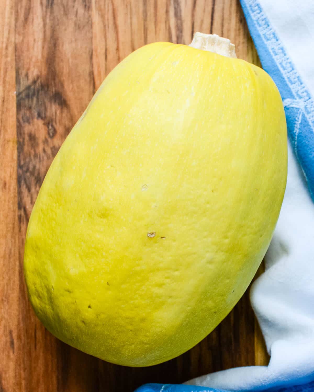 a whole spaghetti squash on a cutting board.