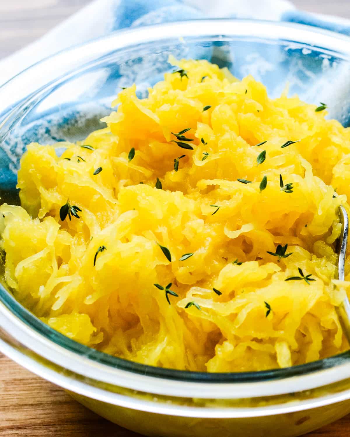 A bowl of spaghetti squash with fresh thyme.