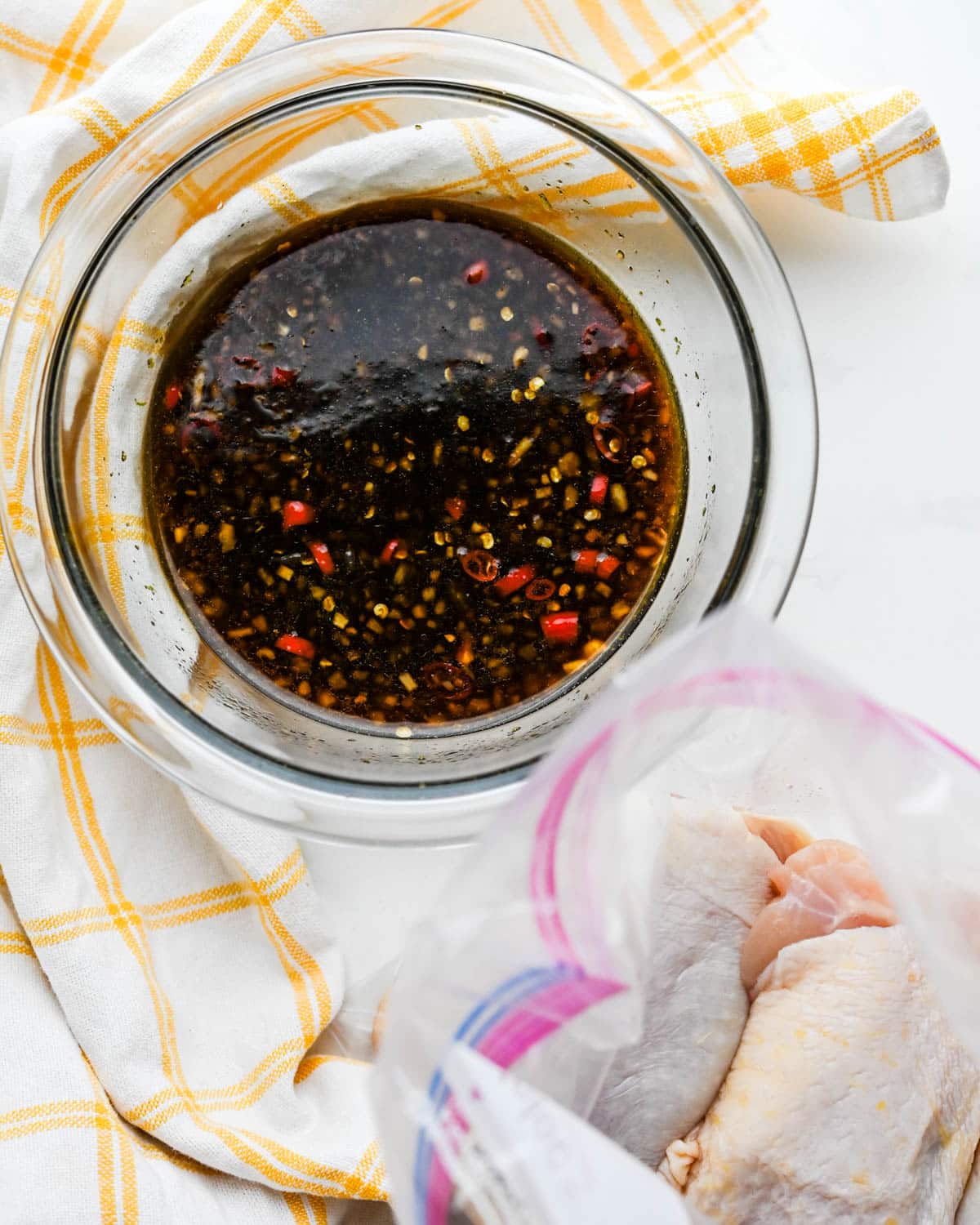 Chicken thighs in a plastic storage bag and the asian marinade ready to pour over them.