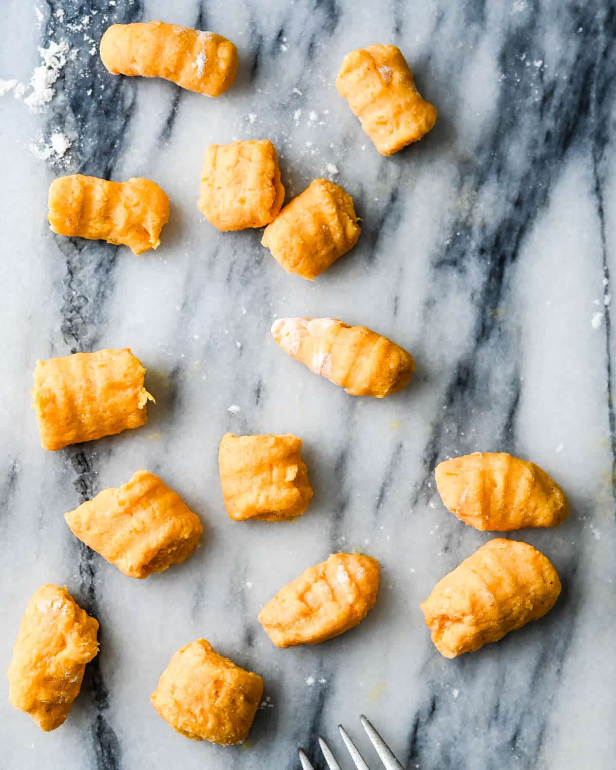 sweet potato gnocchi on a marble pastry board.