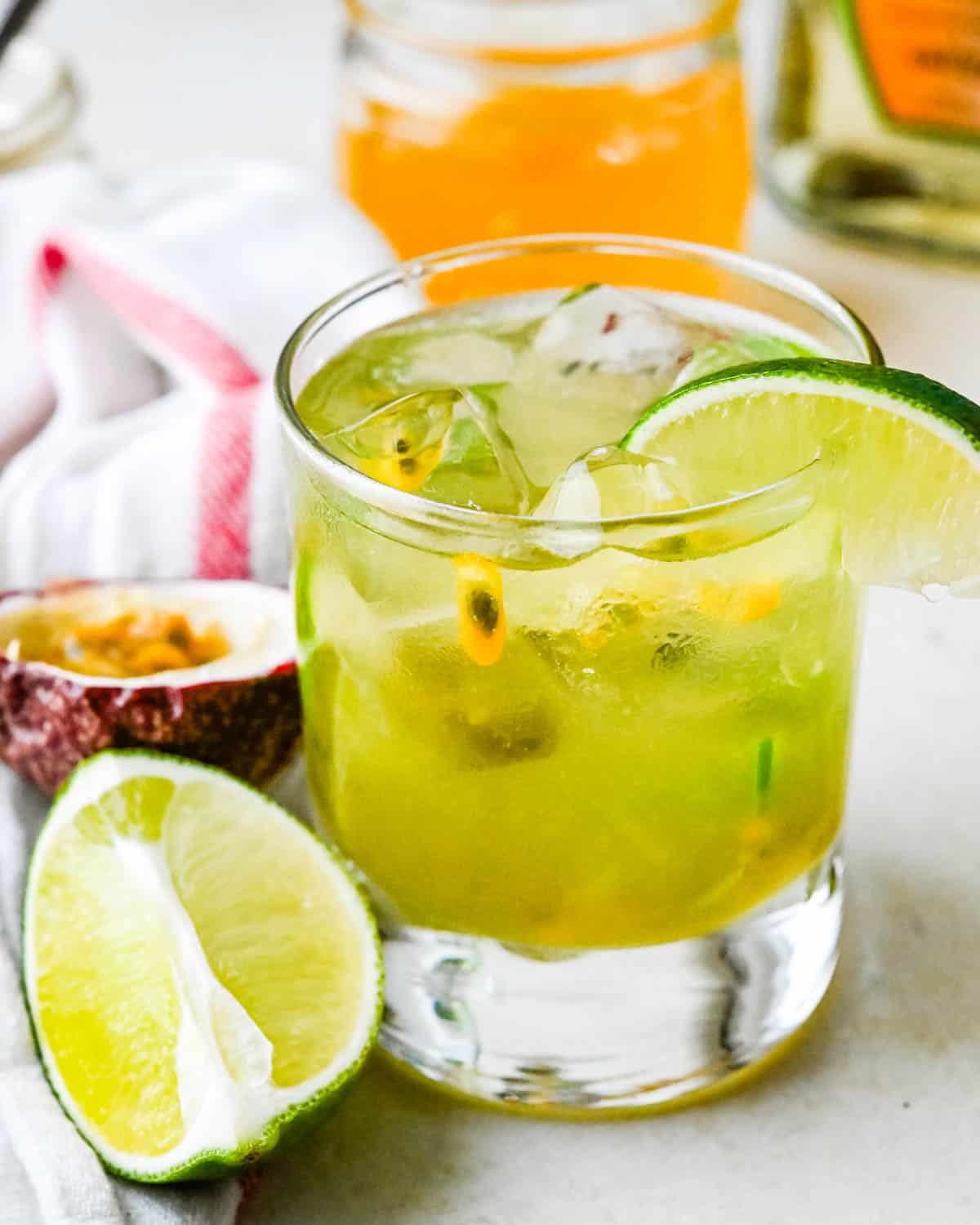 A Freshly made spicy passion fruit margarita with pulp and lime wedge.