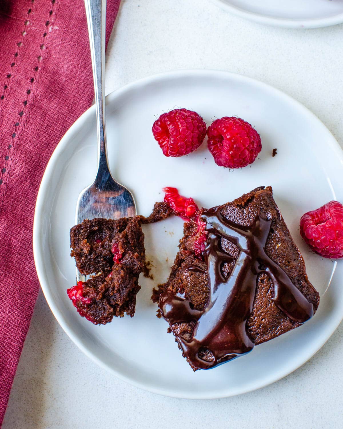 Cutting into the fudgy raspberry brownie on a plate.