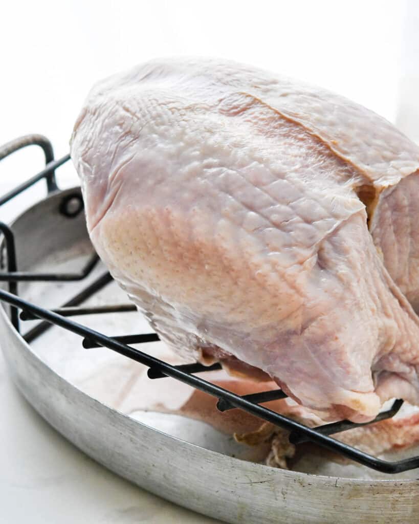 A bone-in turkey breast on a wire rack.