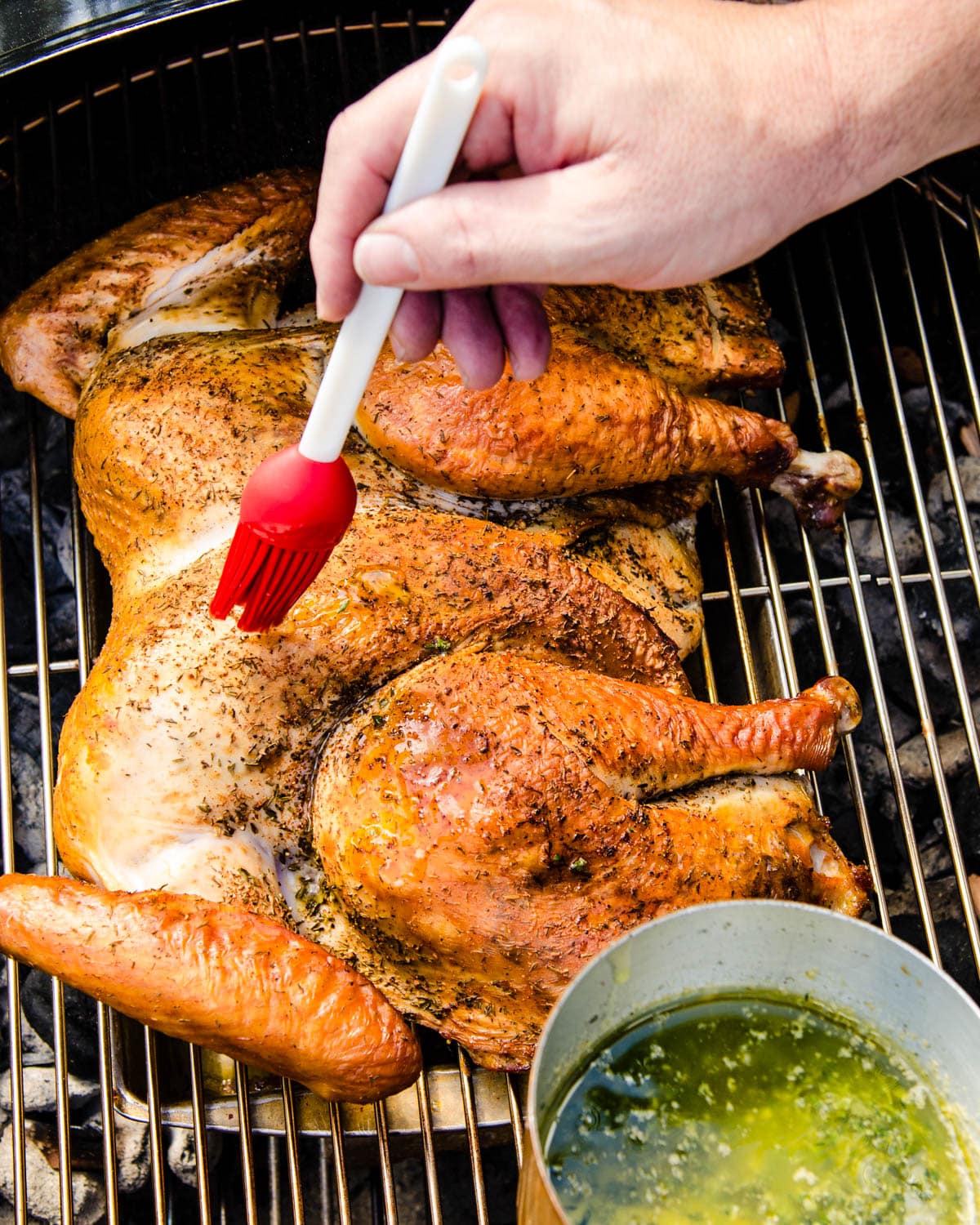 Basting the turkey with herb butter.