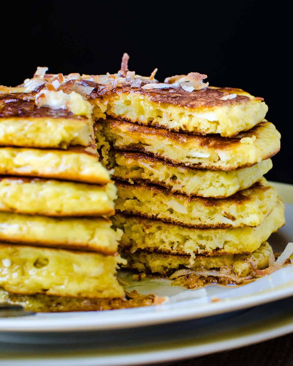 A large stack of orange coconut pancakes.