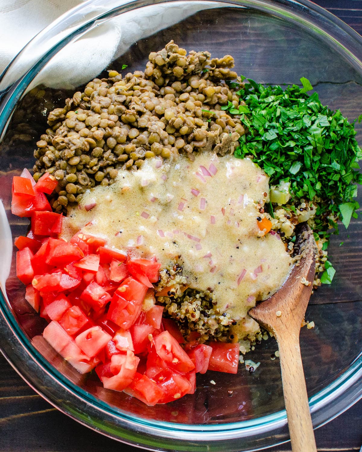 Combining the lentils, diced tomatoes, and quinoa in a bowl.