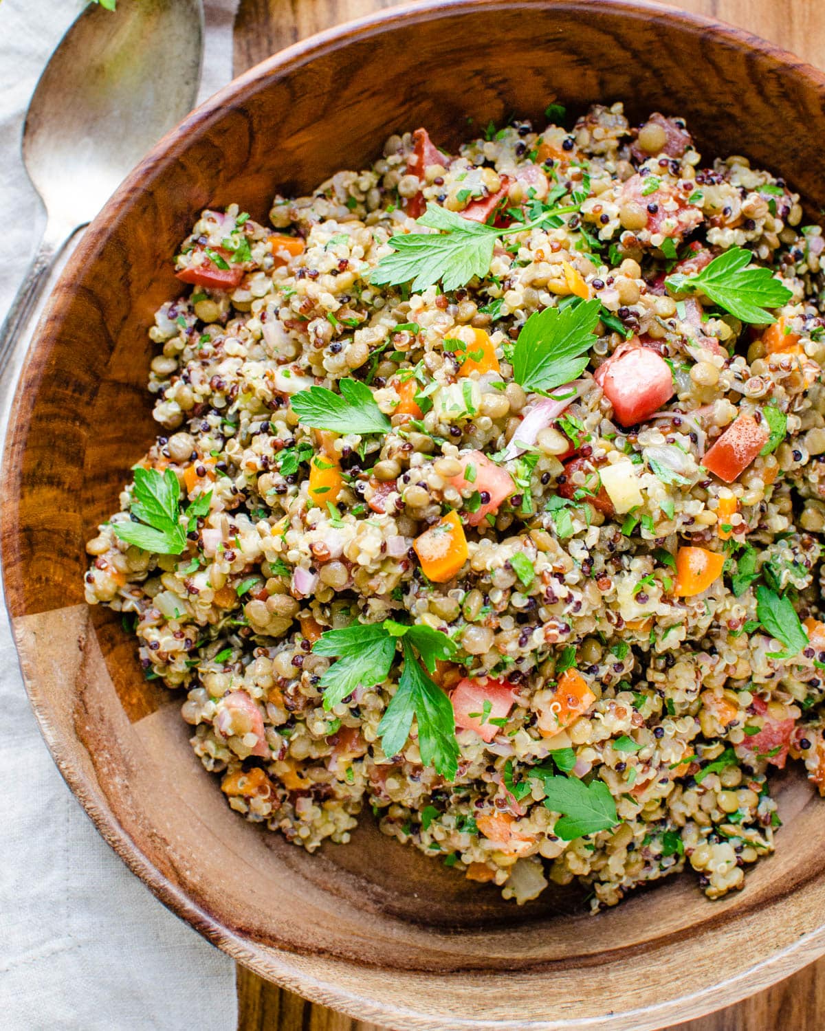 A wooden bowl filled with lentil quinoa salad.