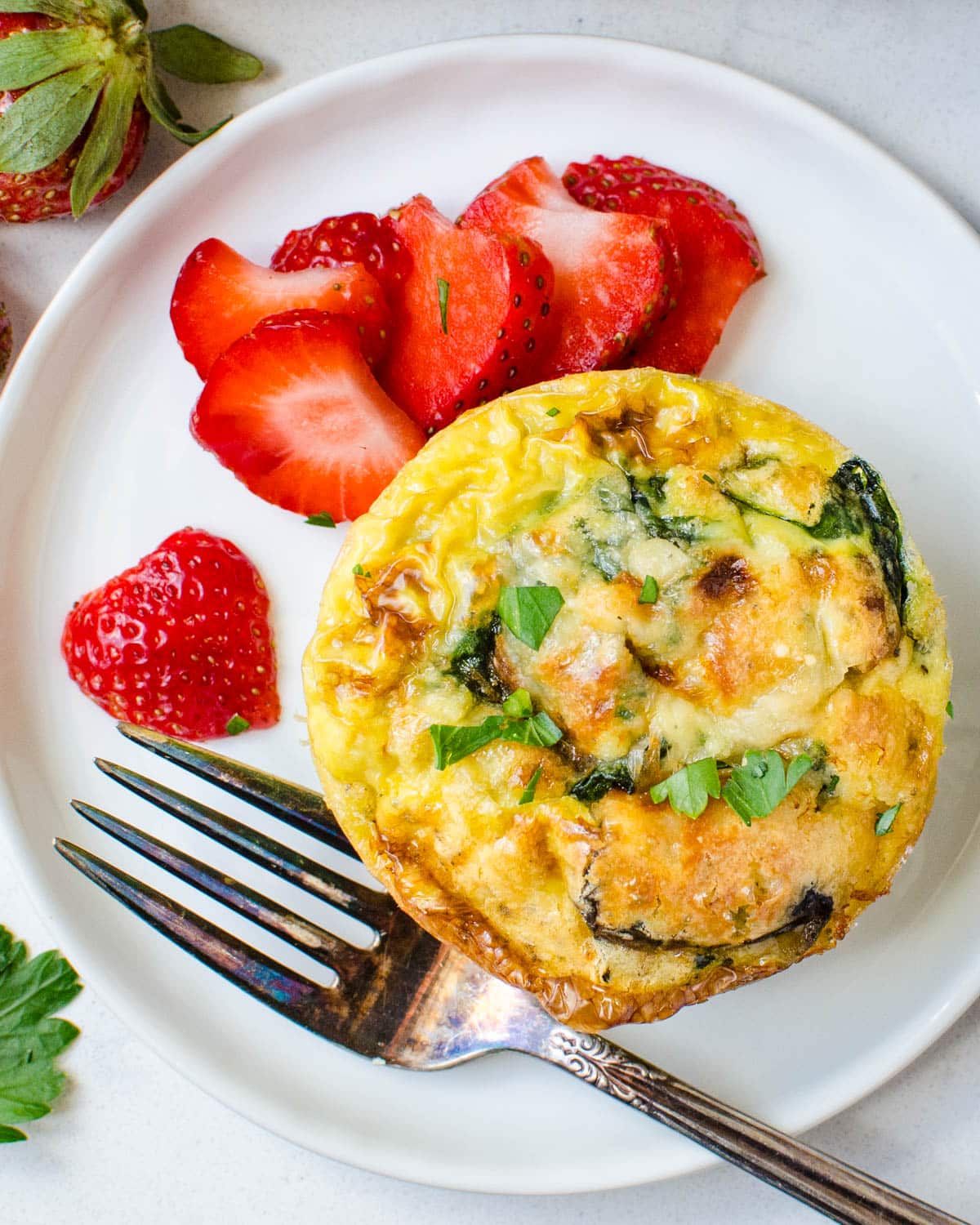 Individual Mushroom and spinach frittatas on a plate with strawberries.