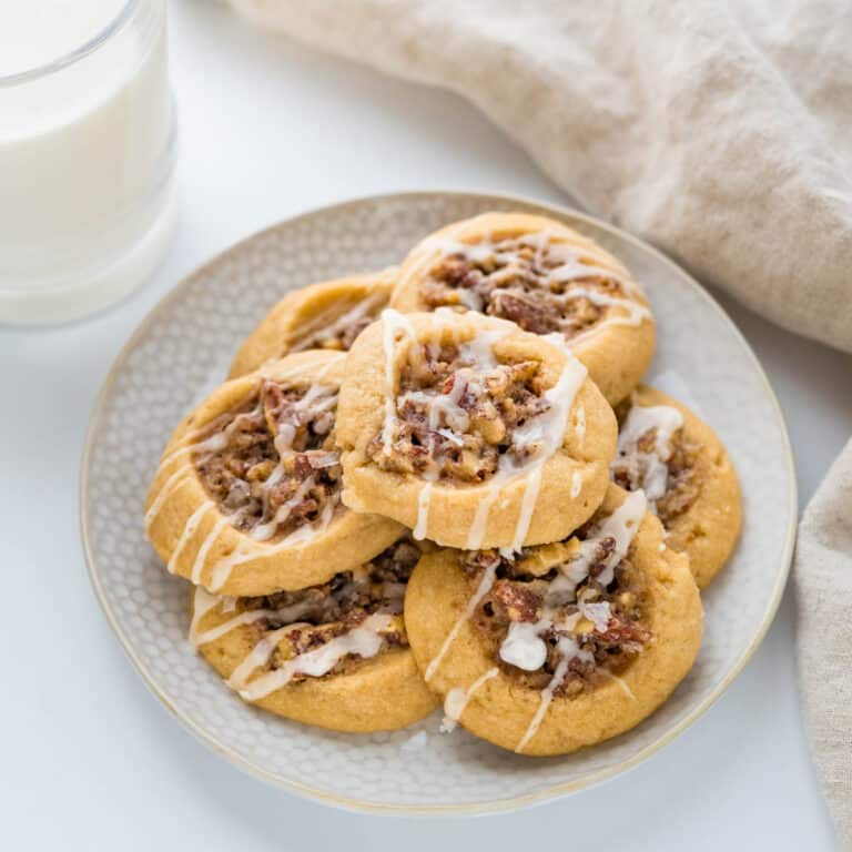 A plate of pecan pie cookies with a glass of milk.