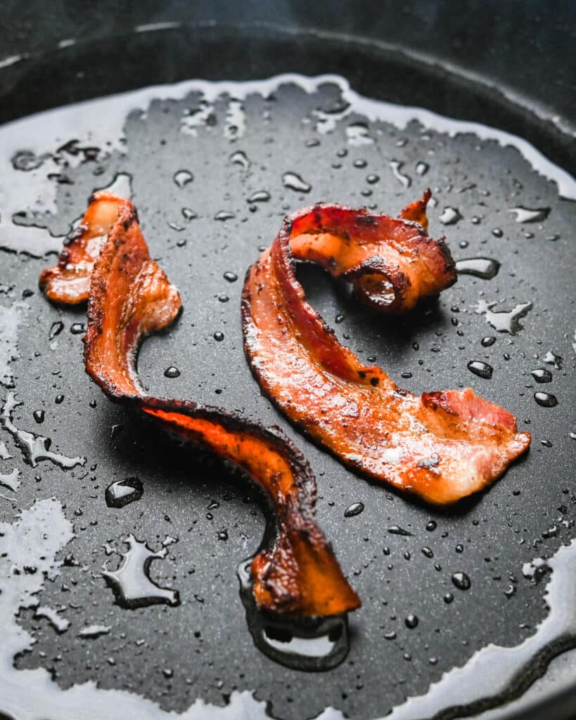 Crisping bacon in a pan.