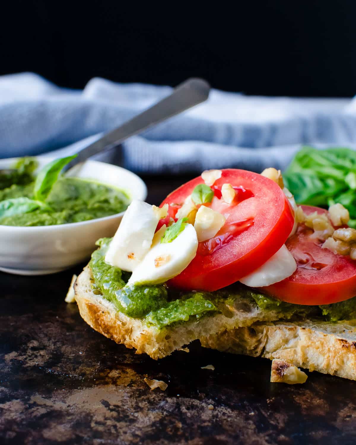 Serving walnut pesto on crostini with cheese and tomato.