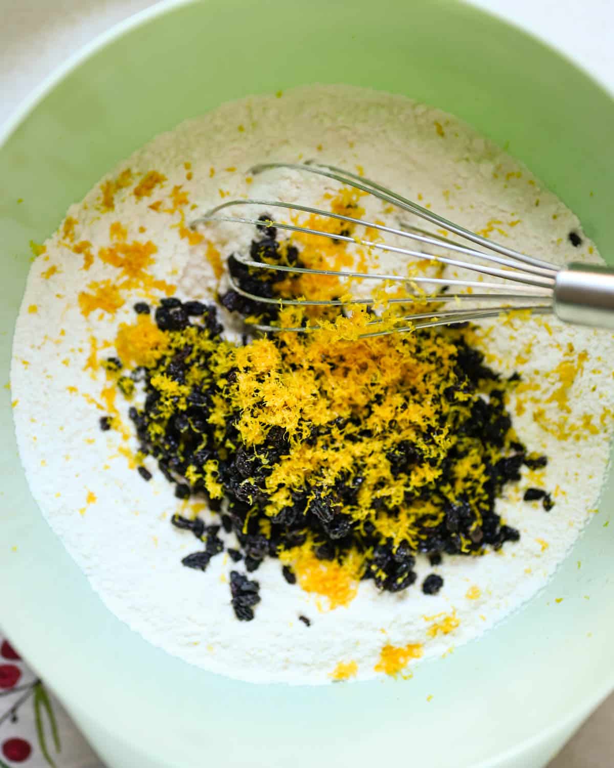Adding orange zest and dried currants to the flour and dry ingredients.