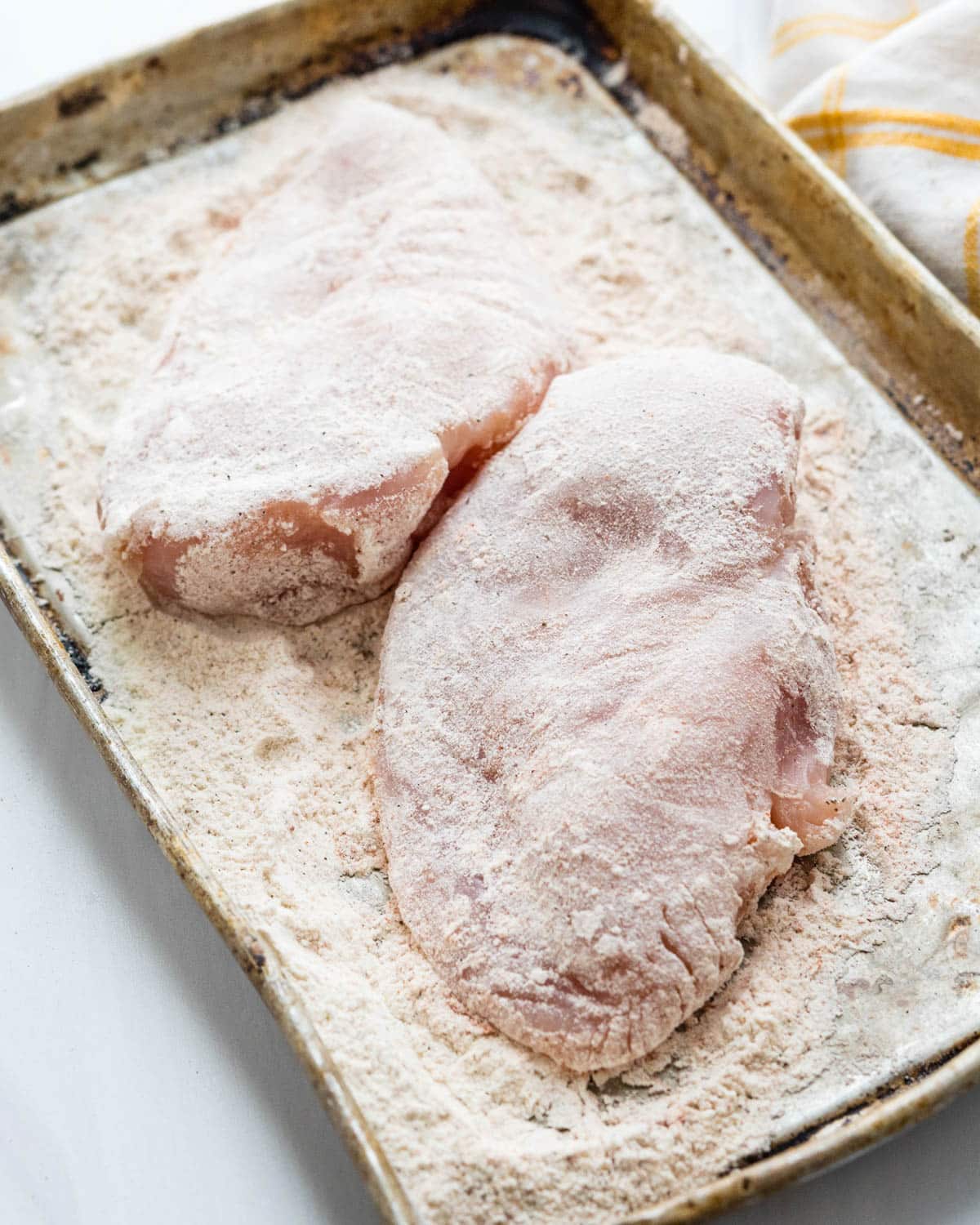 Dredging chicken breasts in seasoned flour.