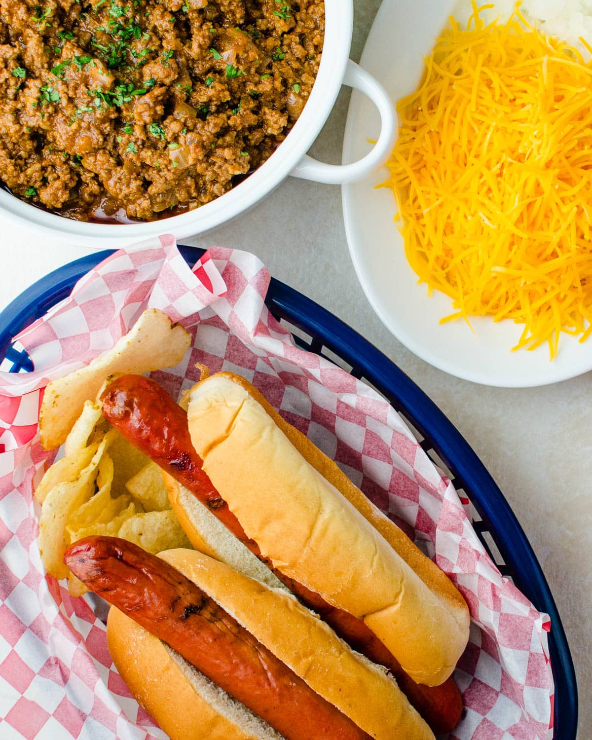 Grilled hot dogs in their buns with toppings on the side.