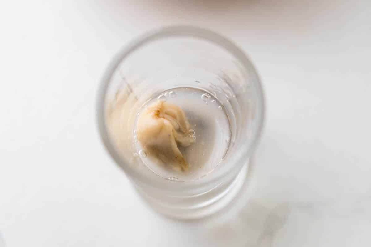Adding an oyster and its liqueur to a shot glass.
