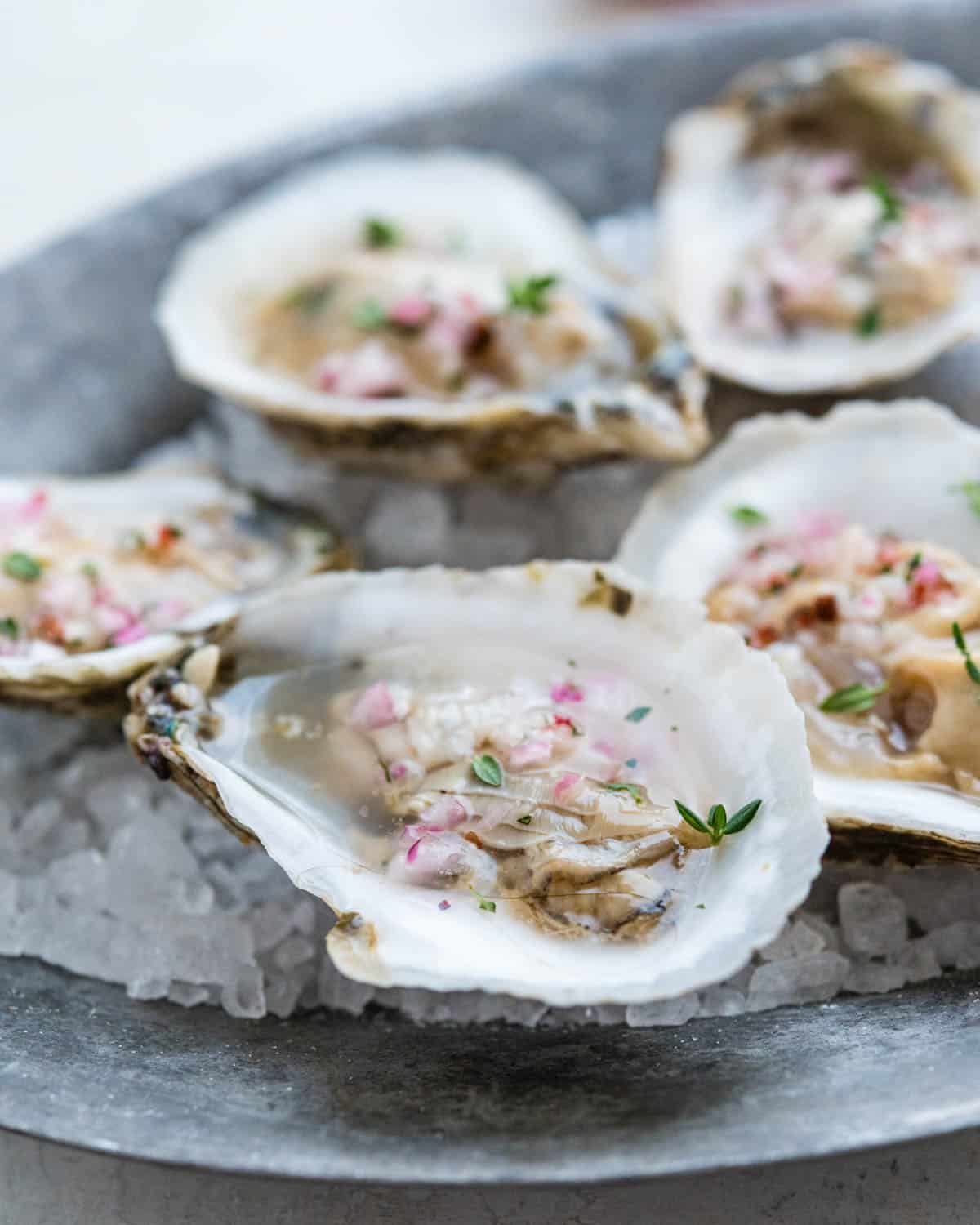Serving oysters on the half shell with a spoonful of mignonette sauce.