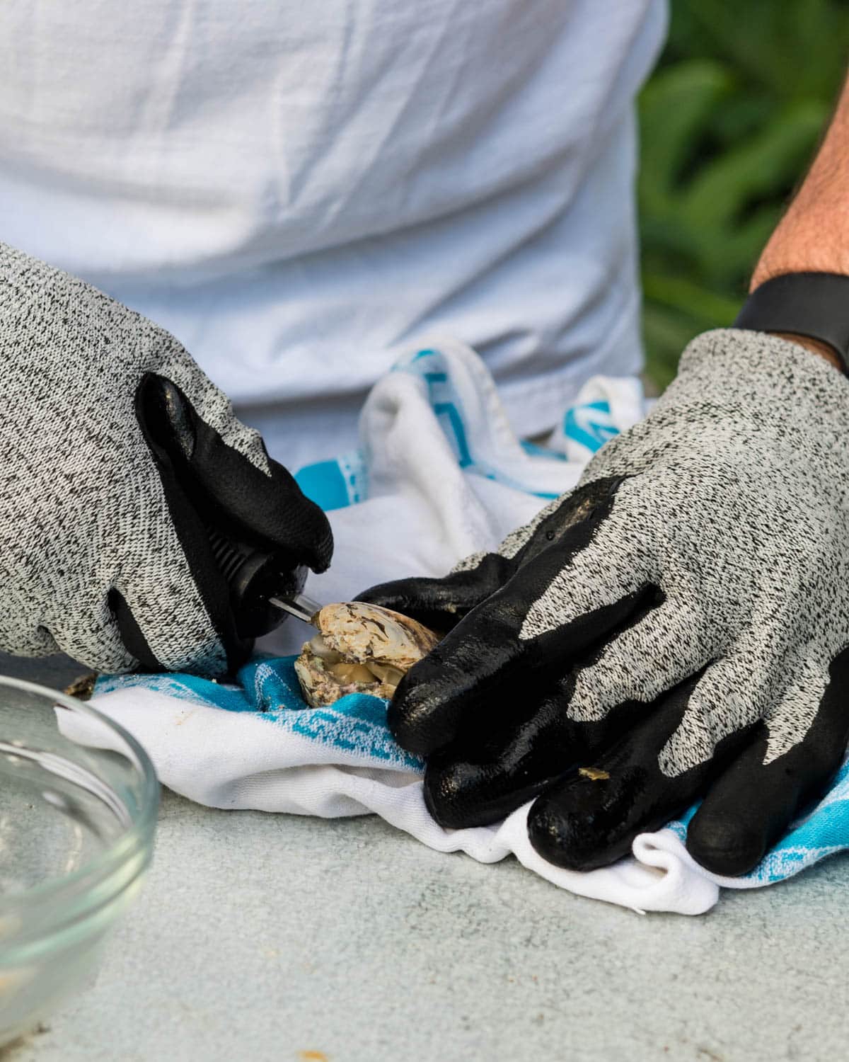 Breaking the hinge of the oyster to shuck it.