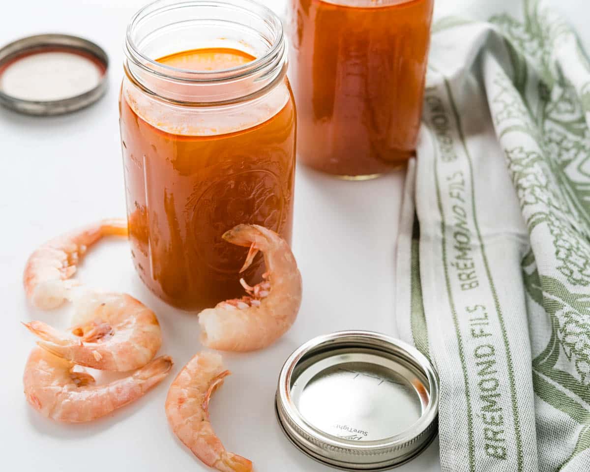 Two jars of stock with shrimp sitting next to them.