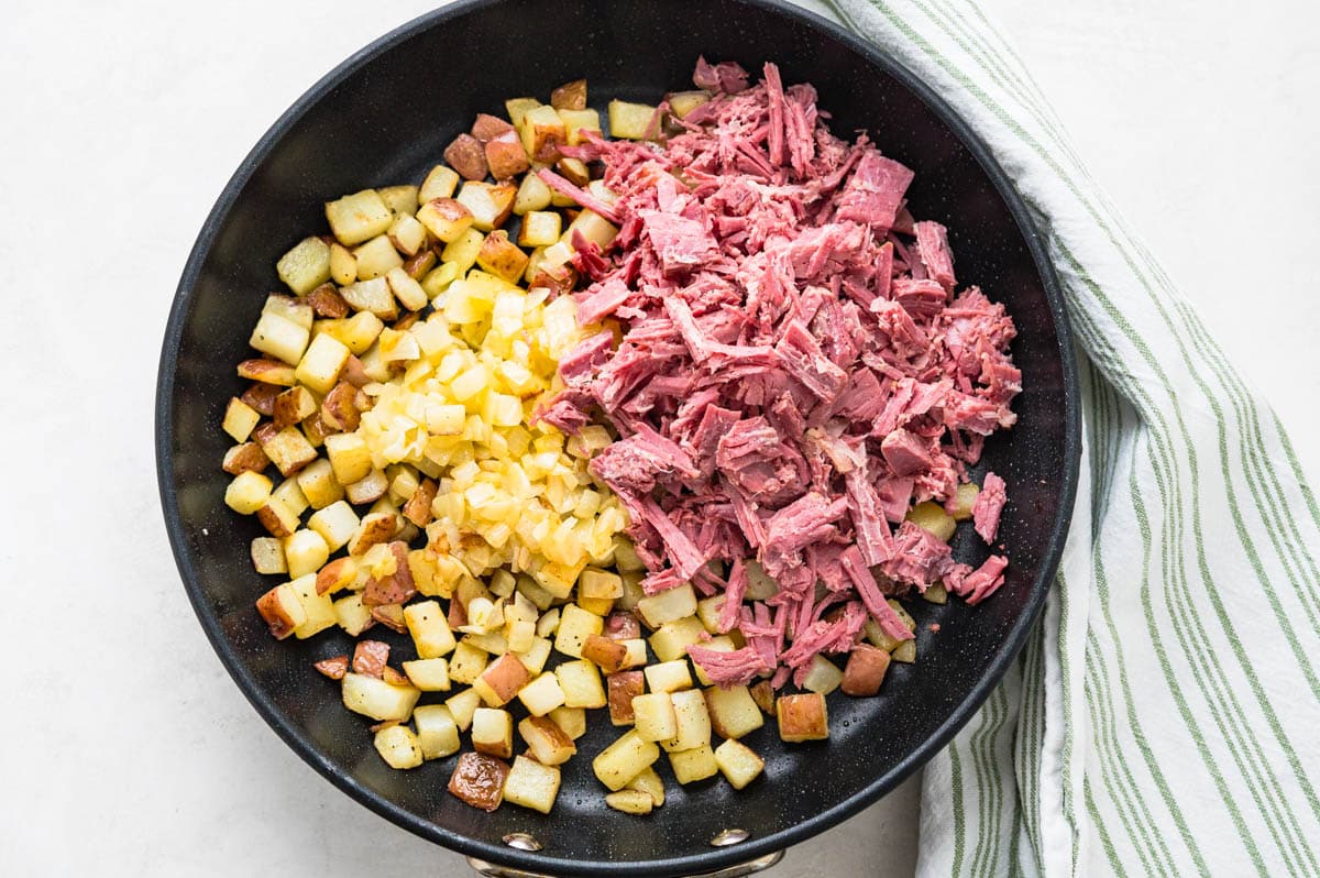 Adding corn beef and onions to the pan.