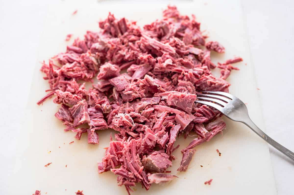 shredding leftover corned beef with a fork.