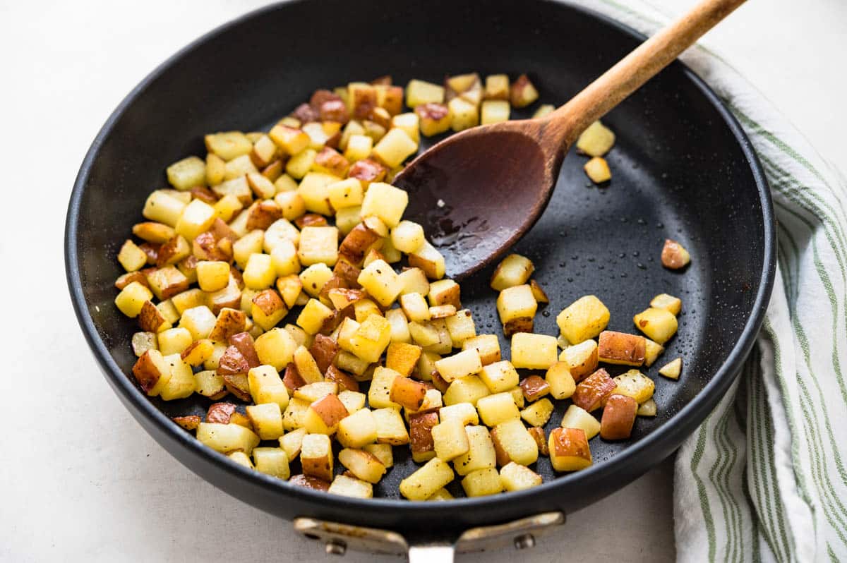 Pan-frying potatoes until golden brown.
