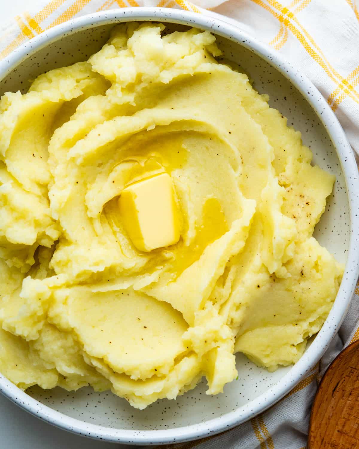 Adding a pat of butter to yukon gold mashed potatoes.