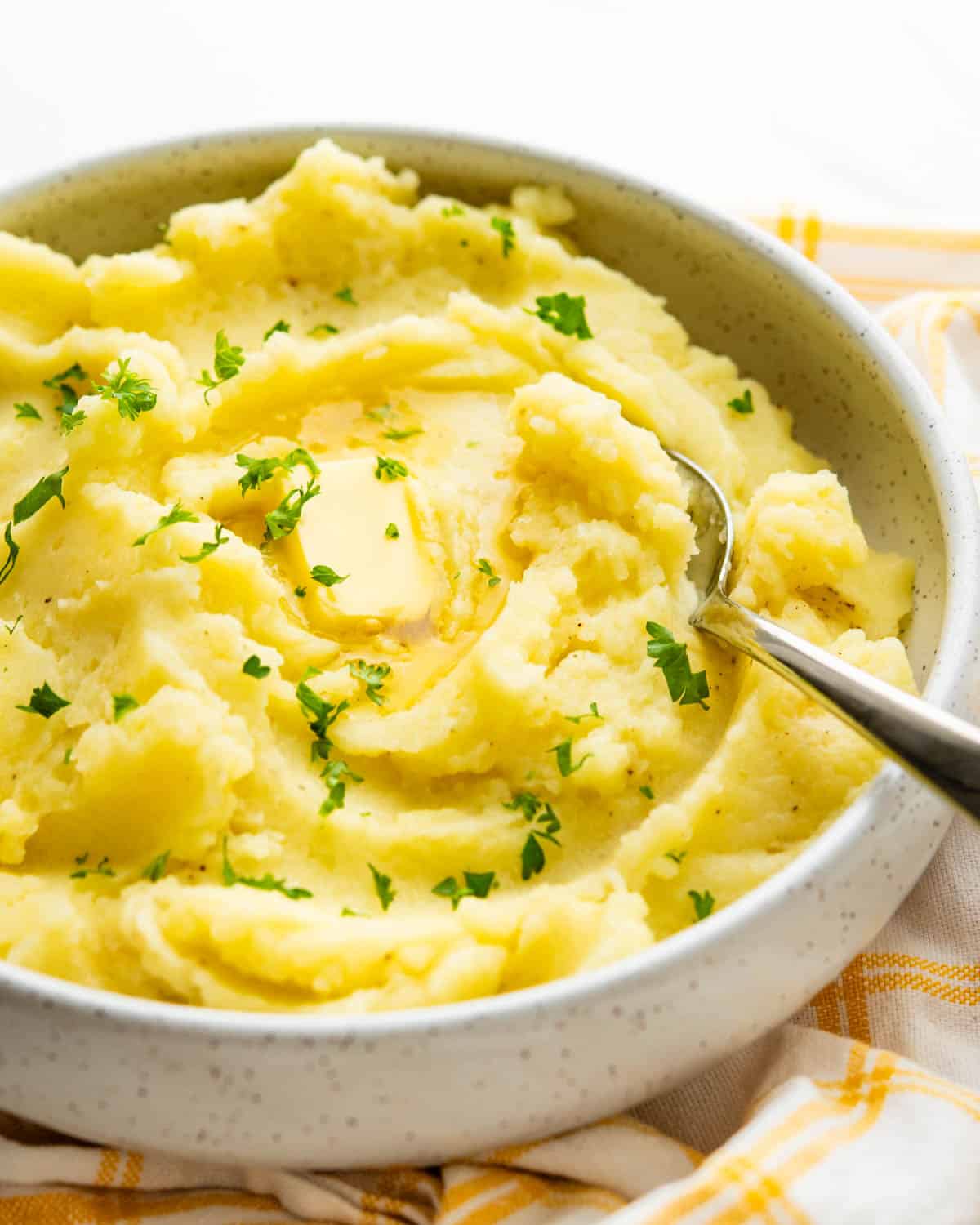 A bowl of creamy riced mashed potatoes with a sprinkle of parsley.