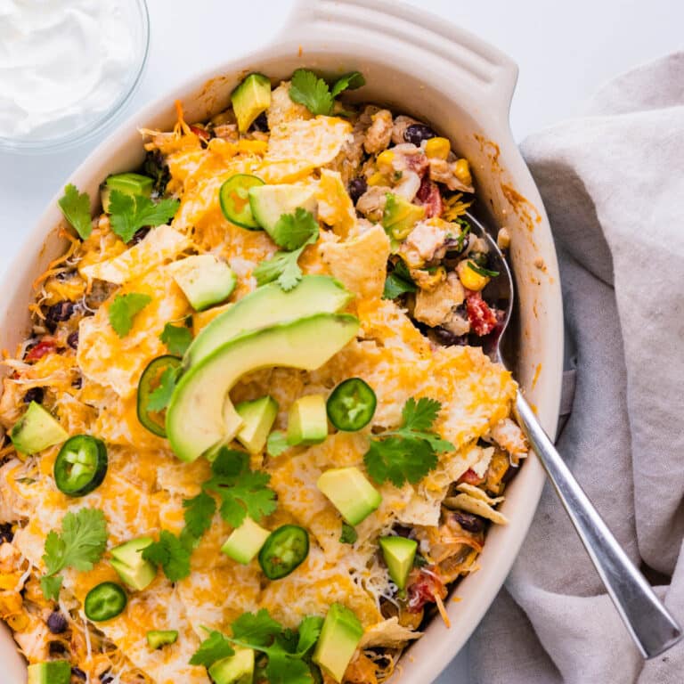 Mexican chicken casserole topped with avocado, cilantro and jalapenos.