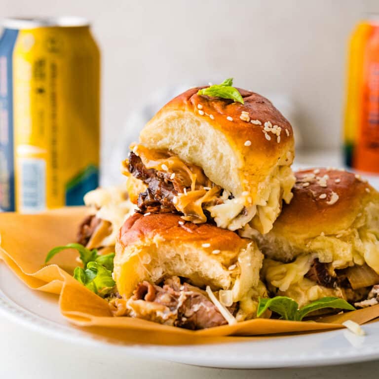 A stack of cheese steak sliders on a plate.