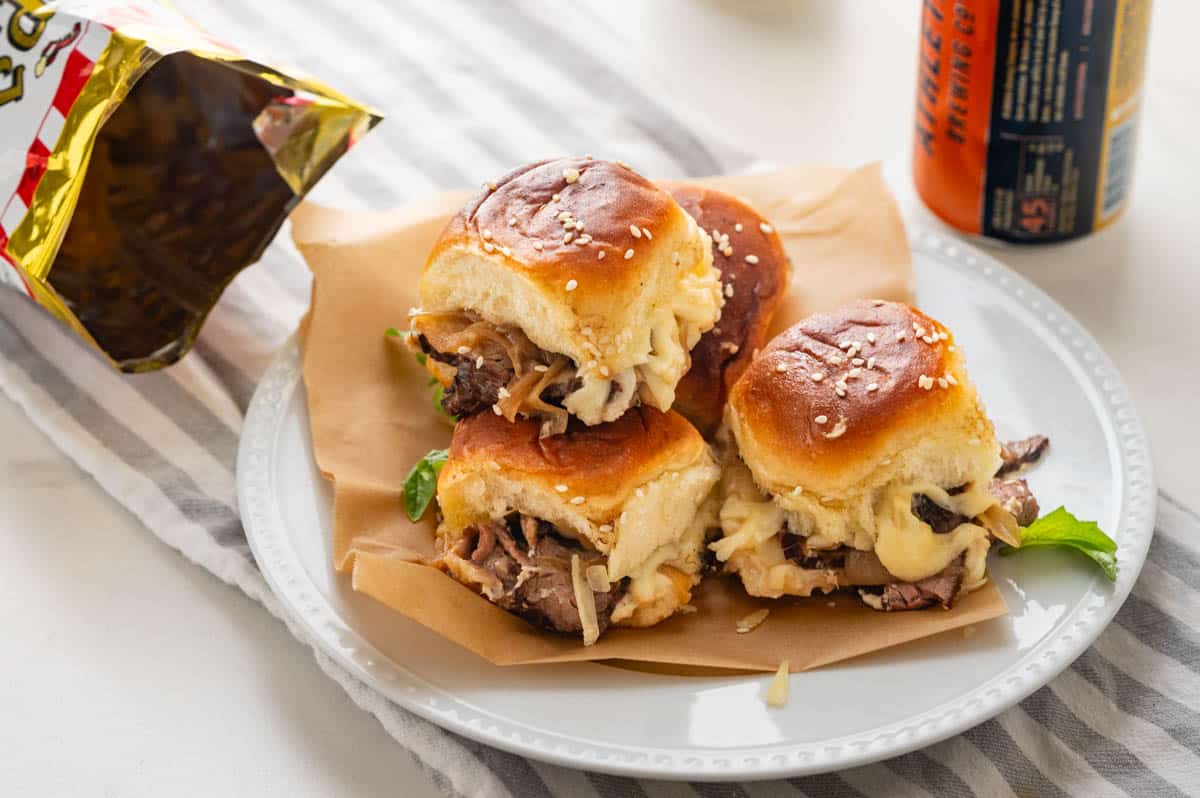 A serving of steak sliders with a bag of chips.