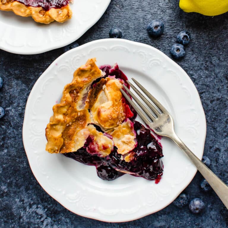 A slice of blueberry pie on a white plate.