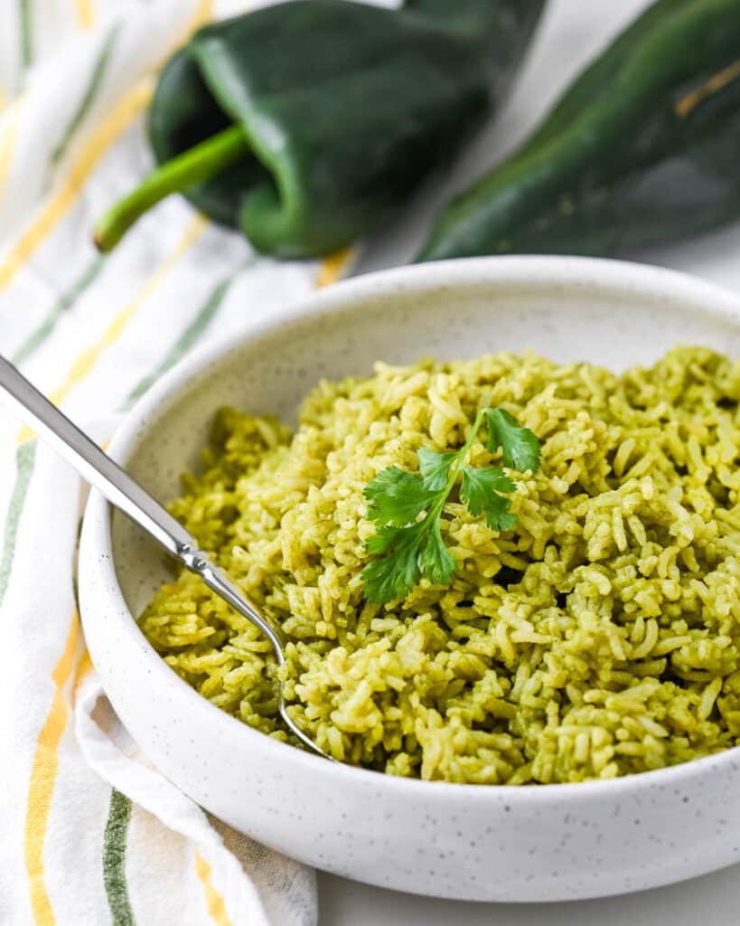Serving arroz verde in a white bowl with serving spoon.