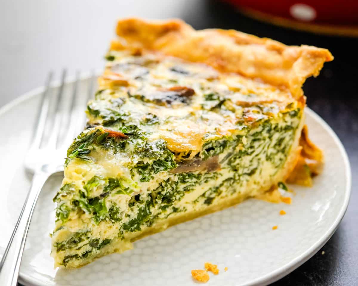 A slice of kale mushroom quiche on a plate. 
