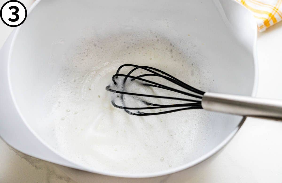 Whisking an egg white until it's very frothy and light.
