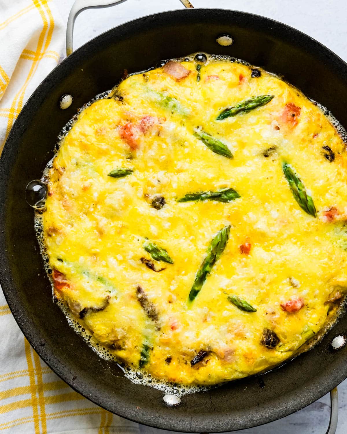 A baked puffy frittata in a skillet.