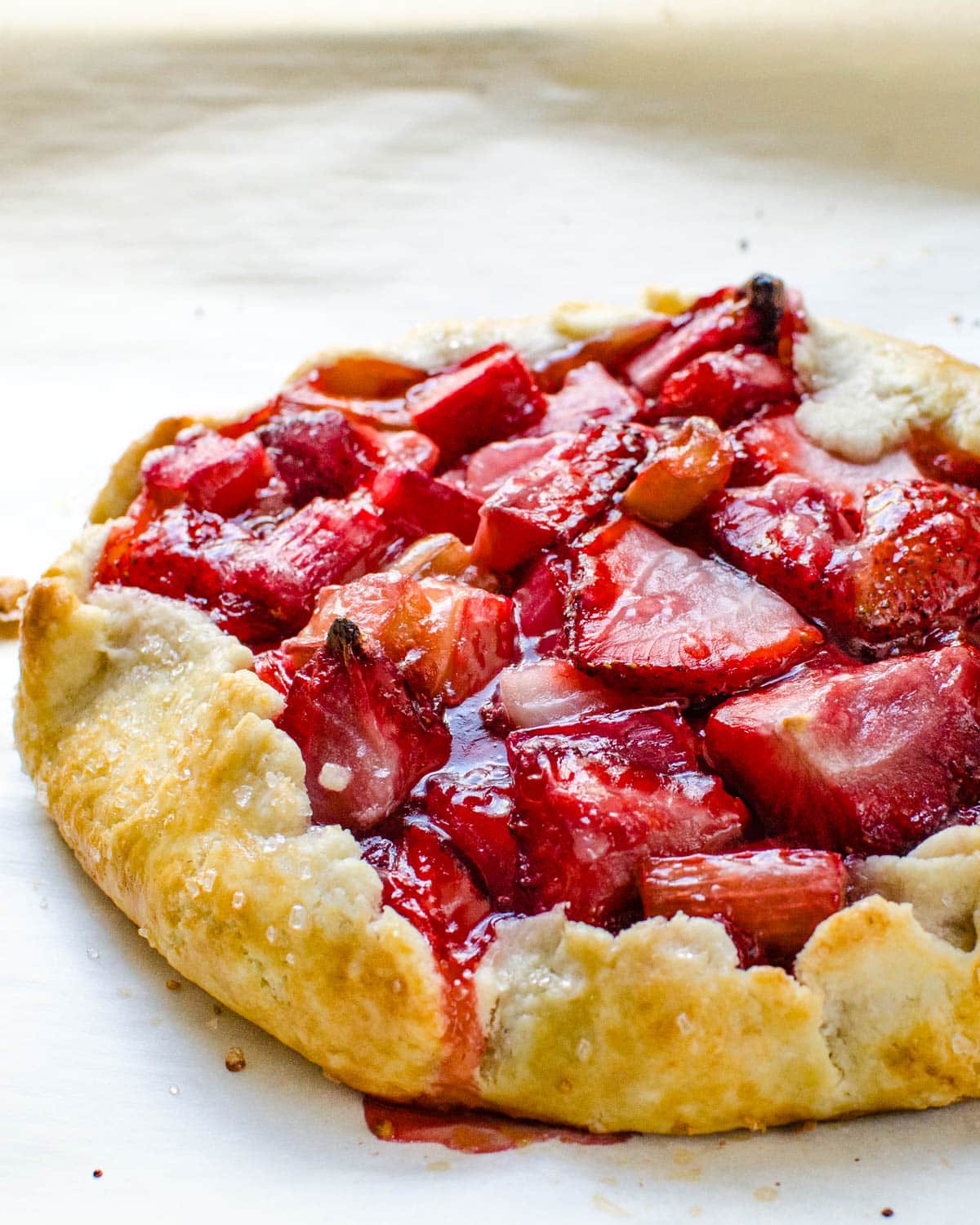 A baked strawberry rhubarb galette on parchment.