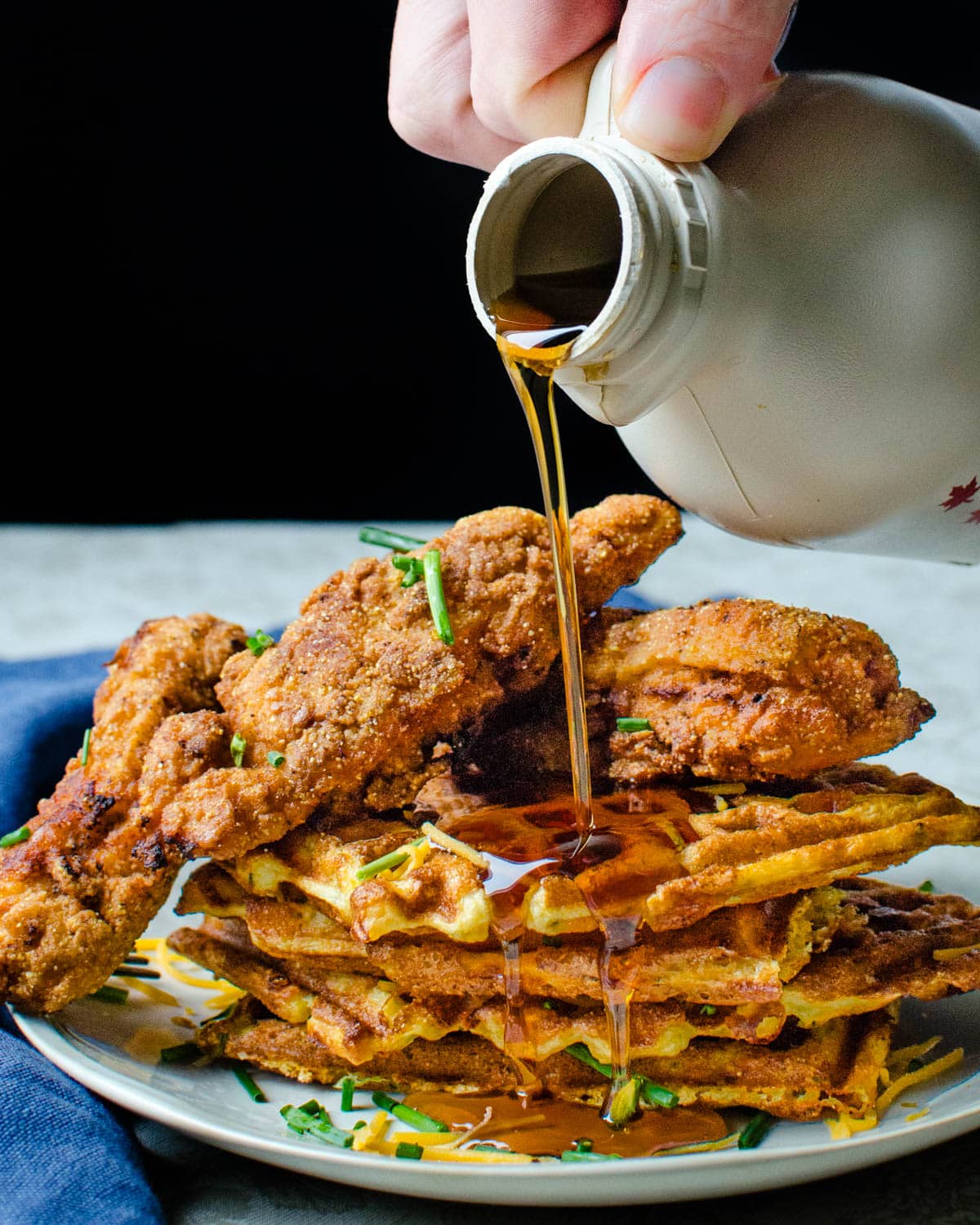 A closeup of the fried chicken and waffles with maple syrup.
