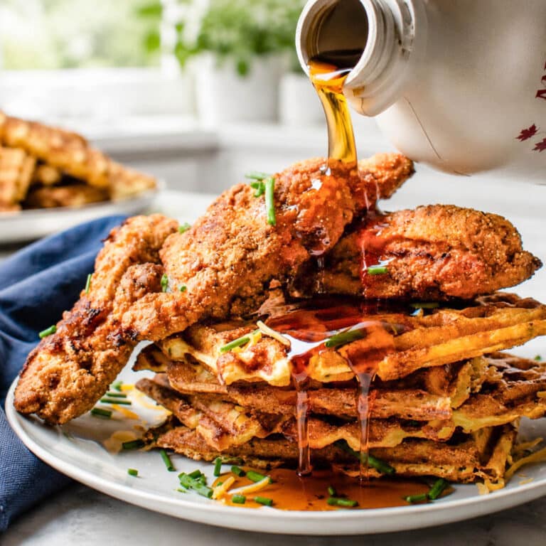 Adding syrup to a stack of crispy waffles and golden fried chicken.