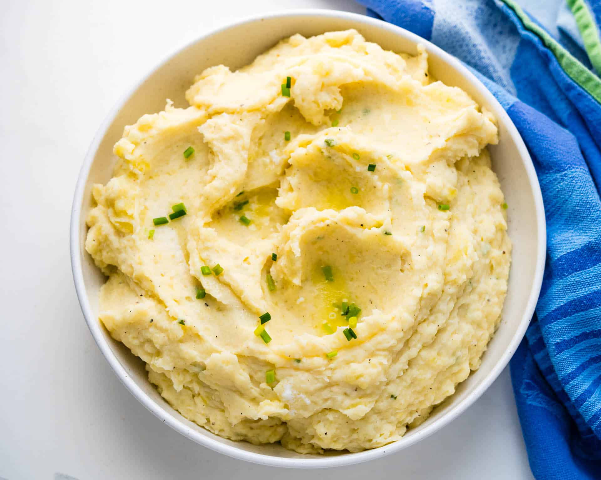 A bowl of mashed potatoes with chives on top.