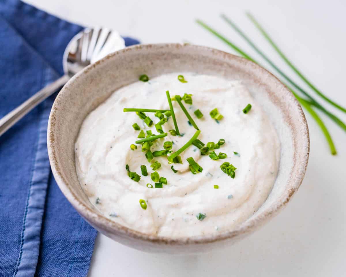 A bowl of the horseradish sauce with chives and a serving spoon.
