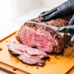 Smoked Prime rib being sliced on a cutting board.