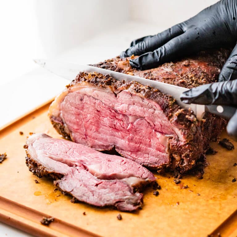 Smoked Prime rib being sliced on a cutting board.