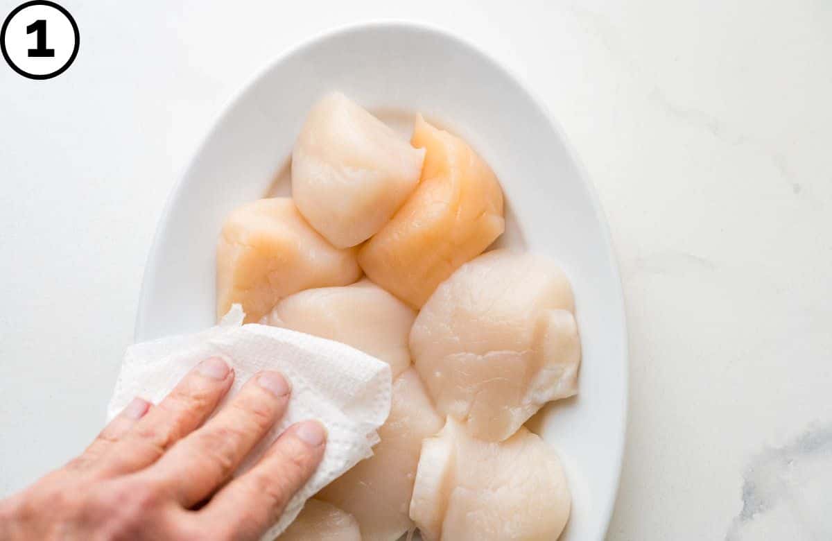 Patting the scallops with paper towels.