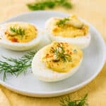 A snack of 3 deviled eggs on a white plate.