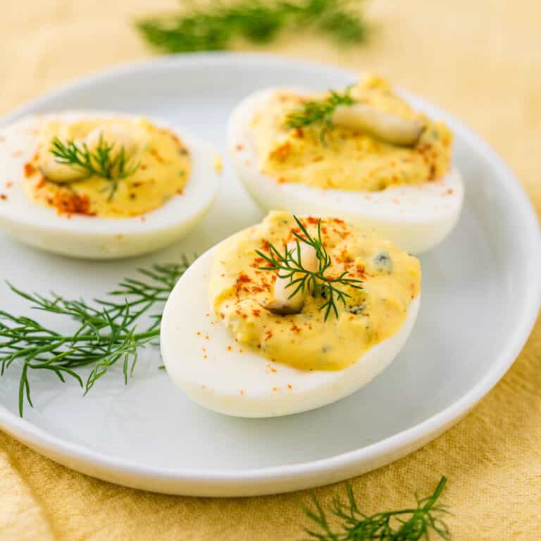A snack of 3 deviled eggs on a white plate.