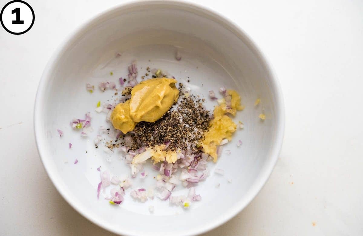 Adding mustard, shallots, garlic, salt and pepper to a small bowl.