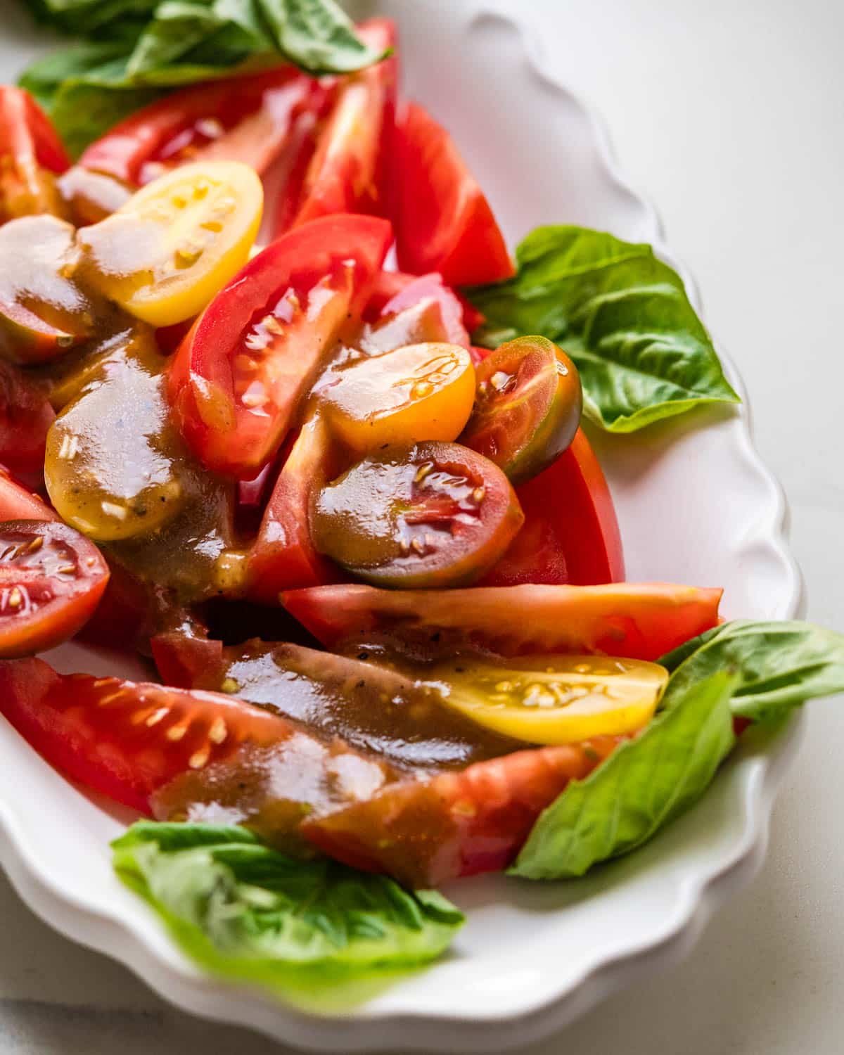 A closeup of the vinaigrette over a platter of sliced tomatoes.